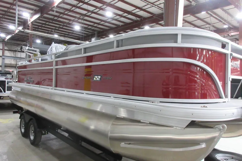 The Image of 2026 Sun Tracker SportFish 22 DLX pontoon boat in a warehouse setting. - 0