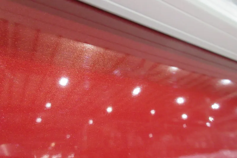 Slide: The Image of Close-up of 2026 Sun Tracker SportFish 22 DLX with glossy red finish and reflections. - 10