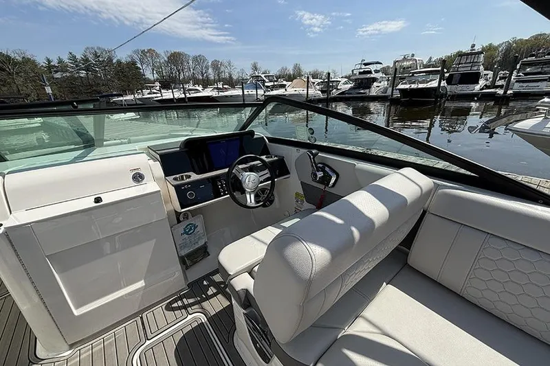 Slide: The Image of 2024 Sea Ray SDX 250 Outboard boat interior with helm, seating, and marina view. - 12
