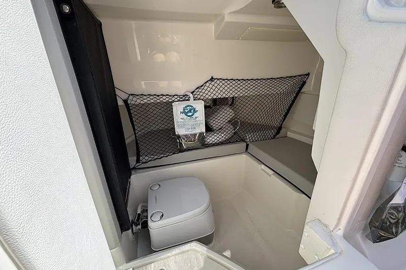 Slide: The Image of 2024 Sea Ray SDX 250 Outboard interior cabin with portable toilet and storage net. - 19