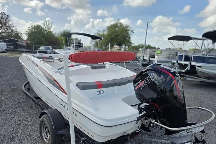 Slide: The Image of 2022 Tahoe T18 boat with outboard motor on a trailer, parked outdoors. - 3