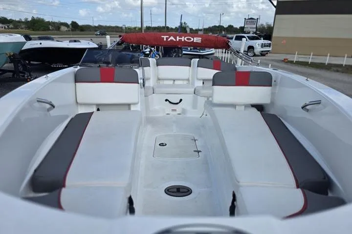 Slide: The Image of 2022 Tahoe T18 boat interior with red and gray seating, docked outdoors. - 8