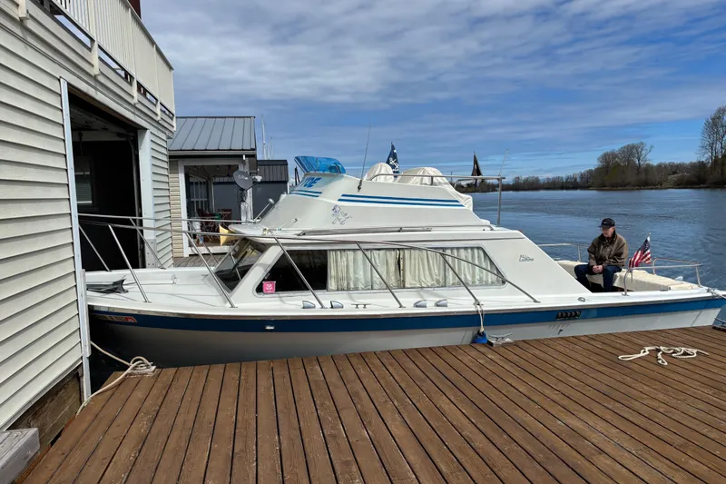 The Image of 1973 Luhrs 28 boat docked by a wooden pier, with a person seated on the deck. - 0