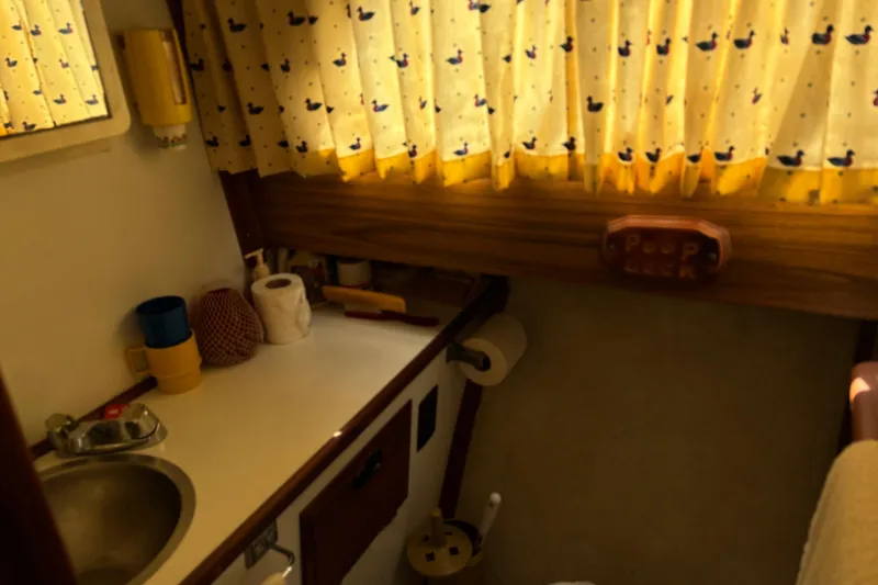 Slide: The Image of 1973 Luhrs 28 boat interior with sink, yellow duck-patterned curtains, and bathroom essentials. - 16