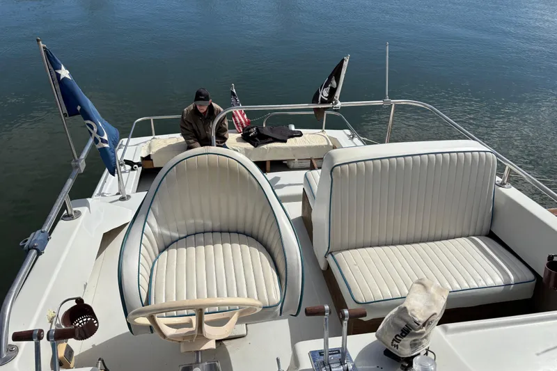 Slide: The Image of 1973 Luhrs 28 boat with white seating, flags, and a person onboard. - 20