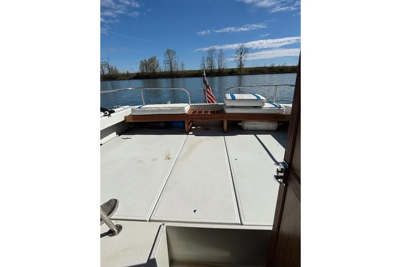 Slide: The Image of 1973 Luhrs 28 boat deck with seating, American flag, and scenic river view. - 5