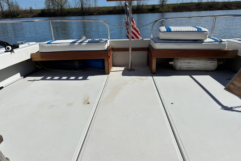 Slide: The Image of 1973 Luhrs 28 boat deck with cushioned seating and American flag on calm water. - 7