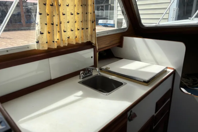 Slide: The Image of 1973 Luhrs 28 boat interior with sink, countertop, and duck-patterned curtains. - 9