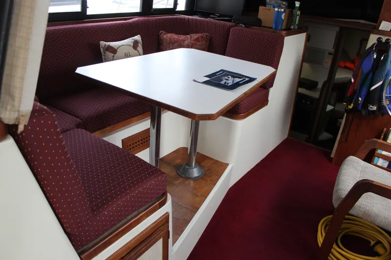 Slide: The Image of Interior of 1985 Carver 32 Convertible boat with dining area and maroon seating. - 11