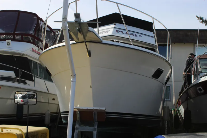Slide: The Image of 1985 Carver 32 Convertible boat docked between other vessels in a marina. - 2