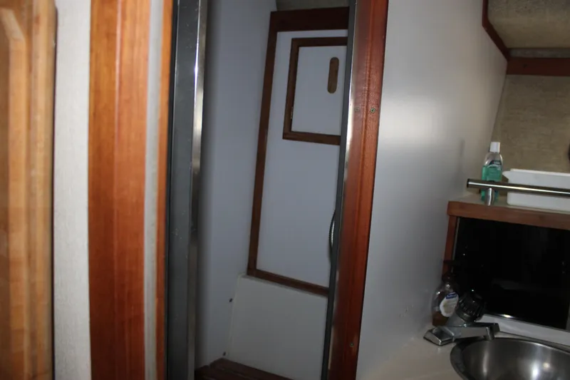 Slide: The Image of Interior of 1985 Carver 32 Convertible boat, featuring a compact bathroom area. - 23