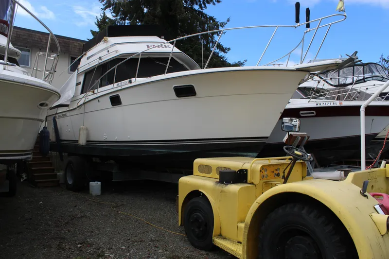 Slide: The Image of 1985 Carver 32 Convertible boat on land, surrounded by other vessels and a yellow tractor. - 30
