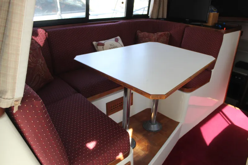 Slide: The Image of Interior of 1985 Carver 32 Convertible with red cushioned seating and white table. - 32