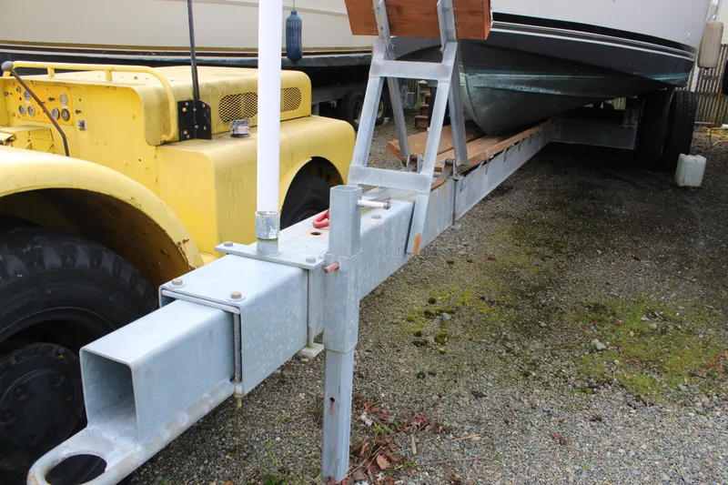 Slide: The Image of 1985 Carver 32 Convertible boat on trailer beside yellow machinery. - 5