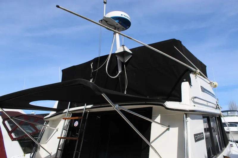 Slide: The Image of 1985 Carver 32 Convertible boat with radar and black canopy under blue sky. - 7