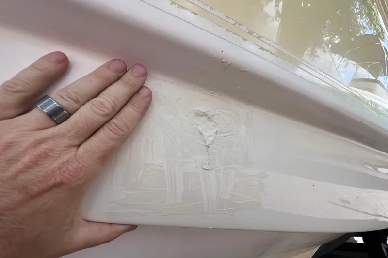 Slide: The Image of Hand inspecting damage on 2008 Scout 222 Dorado boat hull. - 11