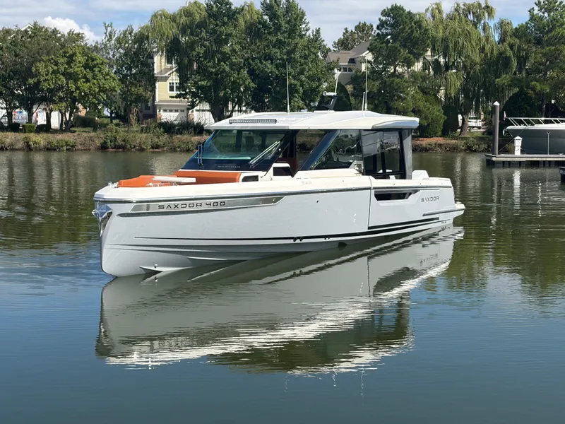 Slide: The Image of A 2027 Saxdor 400 GTC floats on calm water, surrounded by trees and buildings. - 3