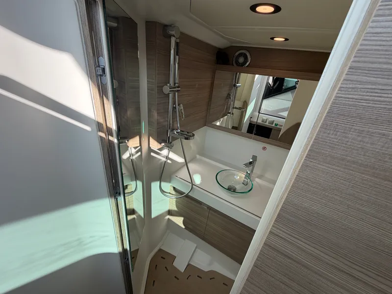 Slide: The Image of The image shows a modern boat bathroom with wood paneling and a glass sink. - 43