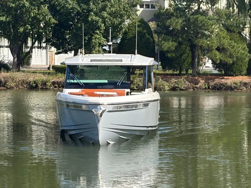Slide: The Image of A modern Saxdor 400 GTC boat from 2027 cruising on a calm river, surrounded by trees. - 2