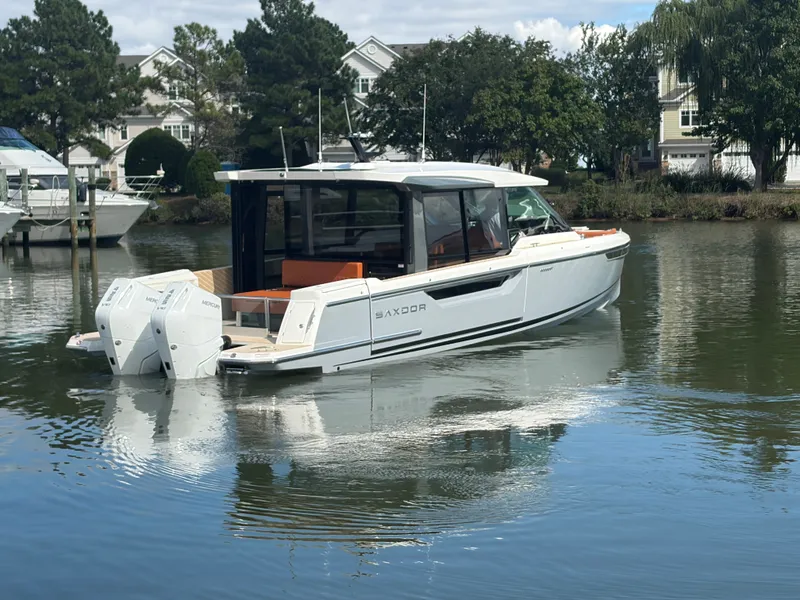 Slide: The Image of Saxdor 400 GTC 2027 on calm water, modern design, twin outboard engines, surrounded by trees and houses. - 7