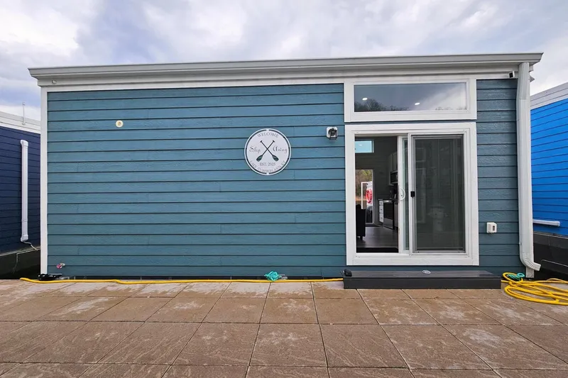 The Image of Modern 2025 houseboat with blue siding and sliding glass door. - 1