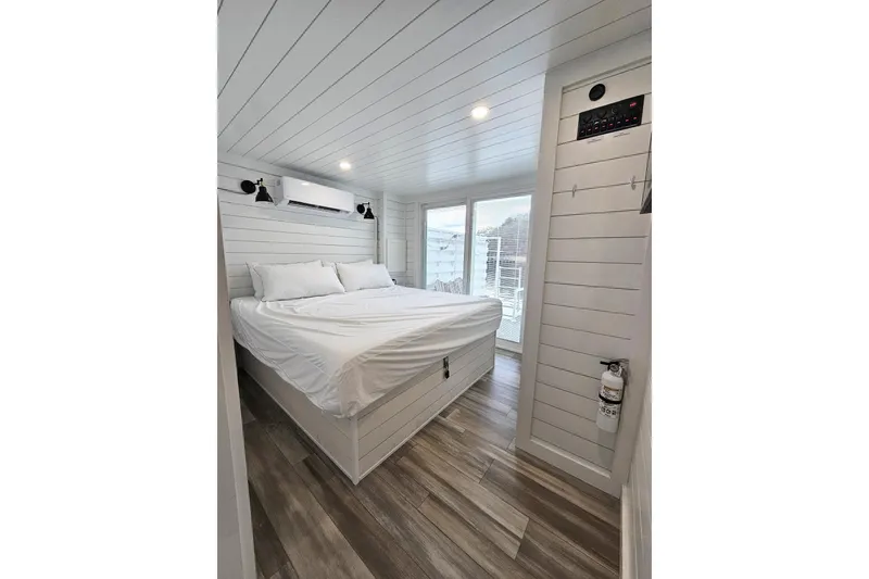 Slide: The Image of Modern 2025 houseboat bedroom with white shiplap walls, large bed, and natural light. - 11