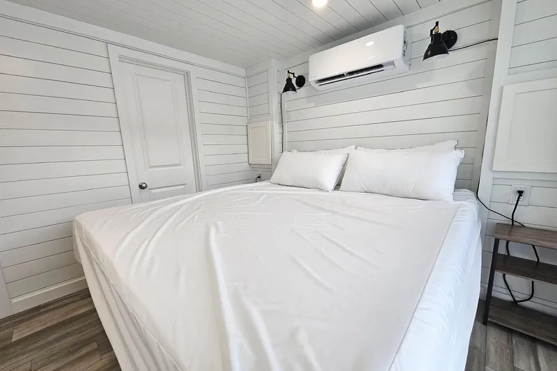 Slide: The Image of Modern houseboat bedroom with white shiplap walls, cozy bed, and air conditioning unit. - 12