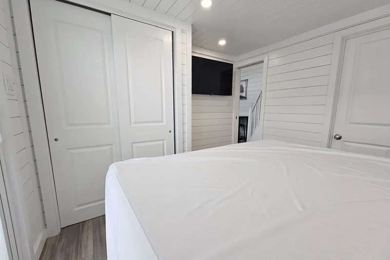 Slide: The Image of Modern houseboat bedroom with white shiplap walls, sliding closet doors, and a wall-mounted TV. - 13