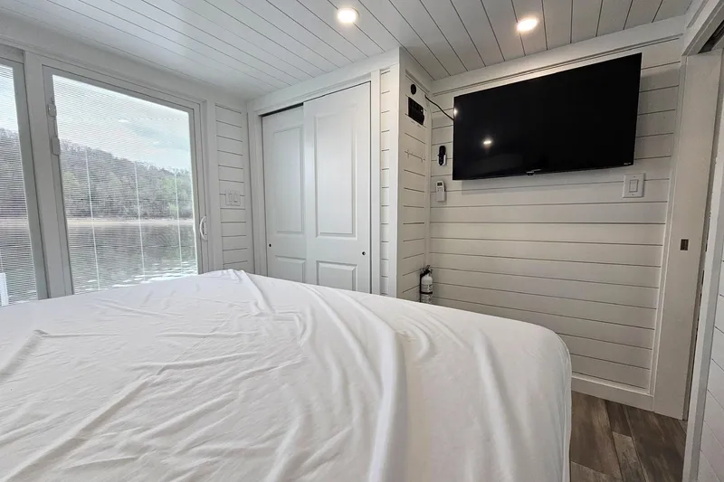 Slide: The Image of Modern houseboat bedroom with TV, large windows, and white interior, 2025 float house model. - 14