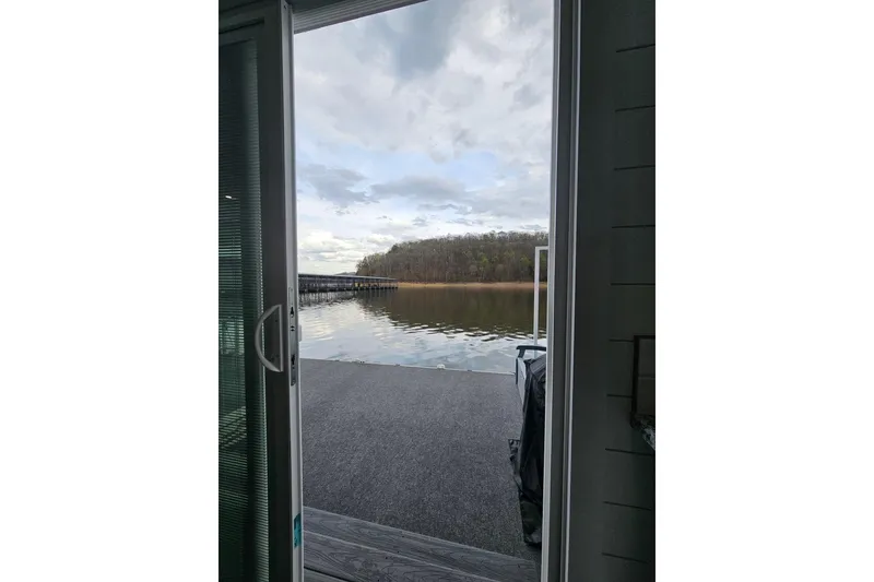 Slide: The Image of Open door view from a 2025 Houseboat float house overlooking a serene lake and cloudy sky. - 17