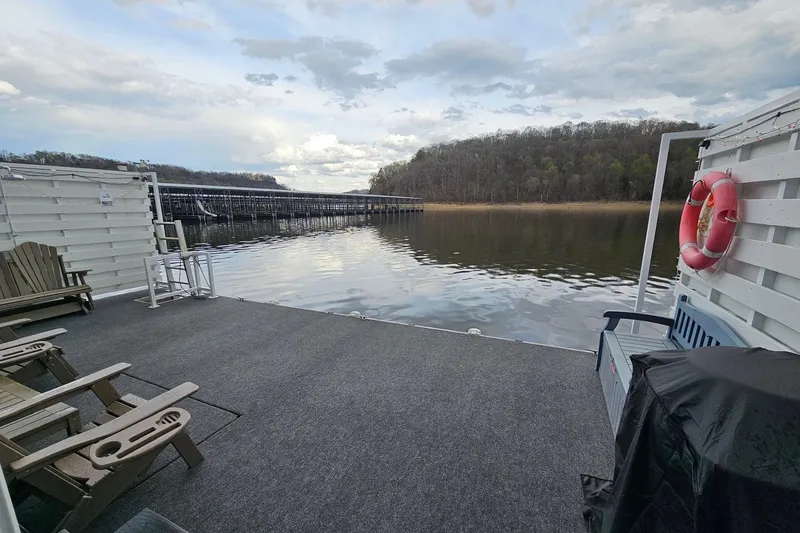 Slide: The Image of Houseboat float house deck with chairs, overlooking serene lake and wooded shoreline, 2025 model. - 18