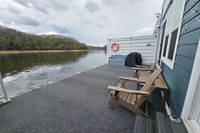 Slide: The Image of Houseboat float house deck with chairs, overlooking serene lake and forested shoreline, 2025 model. - 21