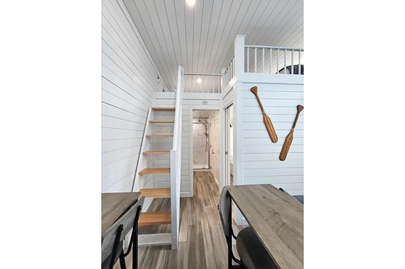 Slide: The Image of Modern 2025 houseboat interior with wooden stairs, white paneling, and decorative oars on the wall. - 8