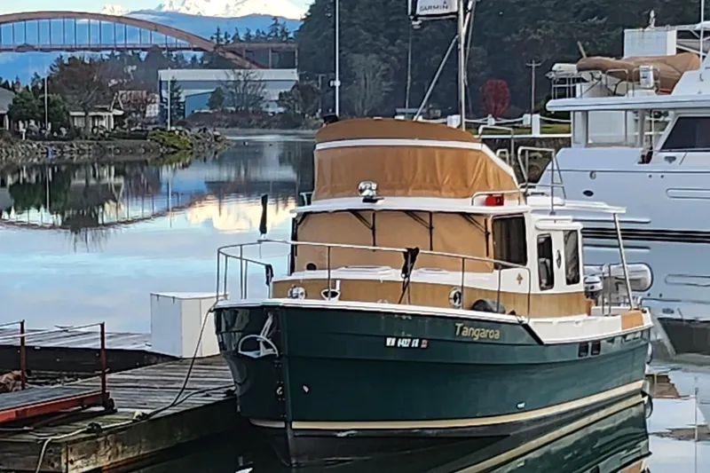 Slide: The Image of 2019 Ranger Tugs R-31 CB docked in a scenic marina with bridge and mountain views. - 2