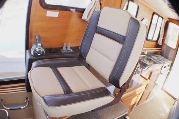 Slide: The Image of Captain's chair in 2019 Ranger Tugs R-31 CB boat interior, featuring wood accents and controls. - 46