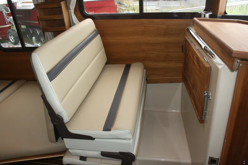 Slide: The Image of Interior of 2019 Ranger Tugs R-31 CB, featuring beige seating and wooden cabinetry. - 50