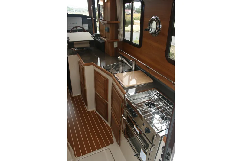Slide: The Image of 2019 Ranger Tugs R-31 CB interior kitchen with wood cabinetry and stainless steel appliances. - 56