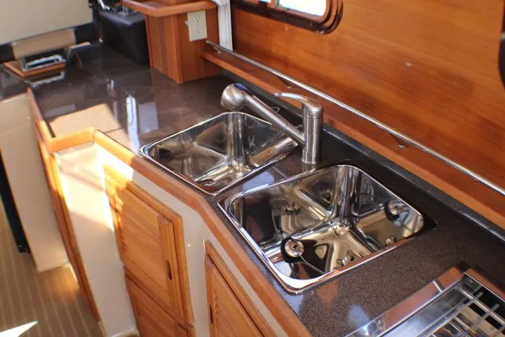 Slide: The Image of 2019 Ranger Tugs R-31 CB galley with dual stainless steel sinks and wooden cabinetry. - 58