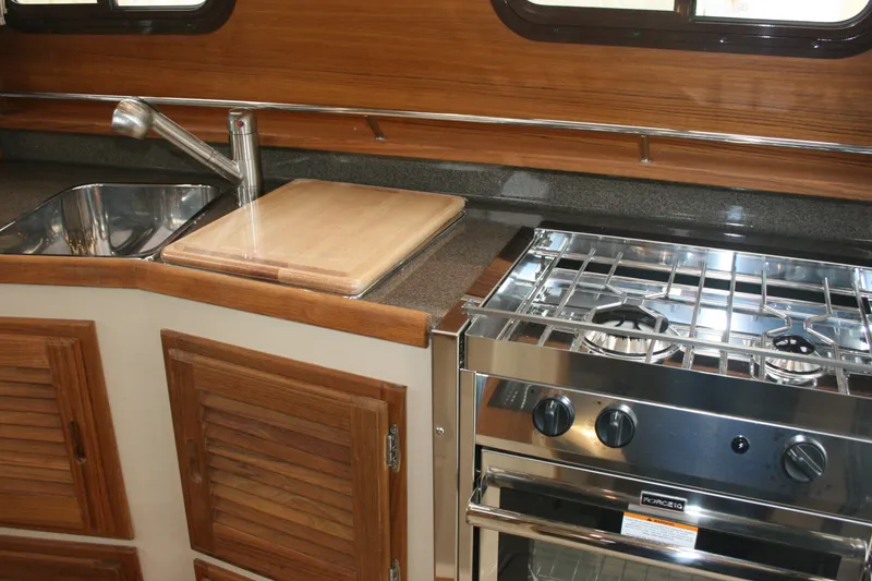 Slide: The Image of 2019 Ranger Tugs R-31 CB kitchen with stainless steel sink, stove, and wooden cabinetry. - 60