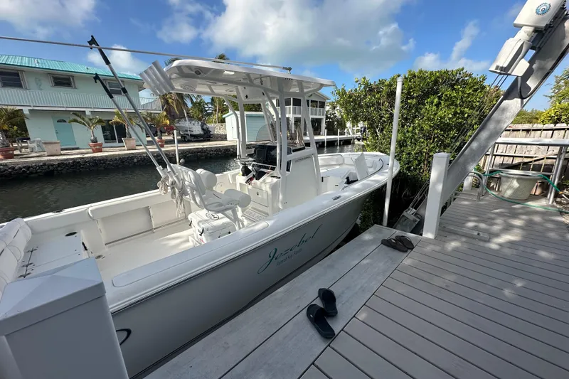 Slide: The Image of 2018 Sea Hunt Ultra 234 boat docked by a canal, under a clear blue sky. - 11