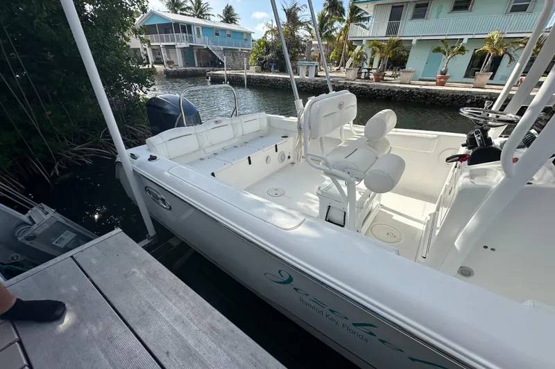 Slide: The Image of 2018 Sea Hunt Ultra 234 boat docked near waterfront homes in a tropical setting. - 12