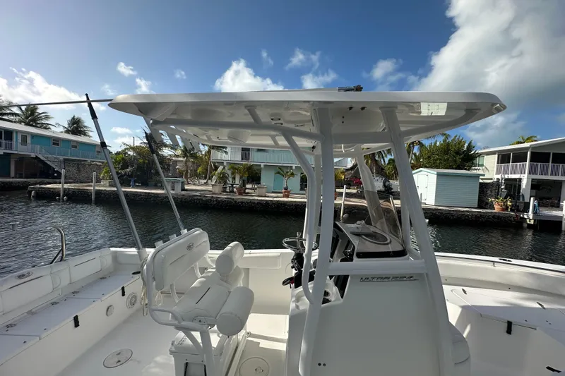 Slide: The Image of 2018 Sea Hunt Ultra 234 boat docked by waterfront homes under a clear sky. - 13