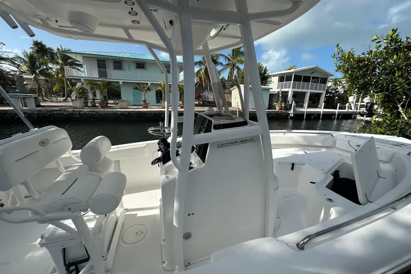 Slide: The Image of 2018 Sea Hunt Ultra 234 boat interior with helm, dockside view, and waterfront homes. - 14