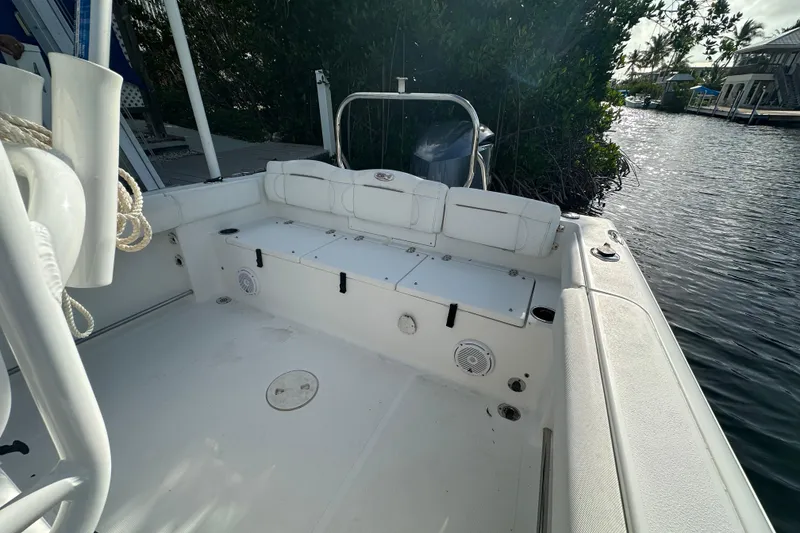 Slide: The Image of 2018 Sea Hunt Ultra 234 boat interior with seating and storage, docked by water. - 15