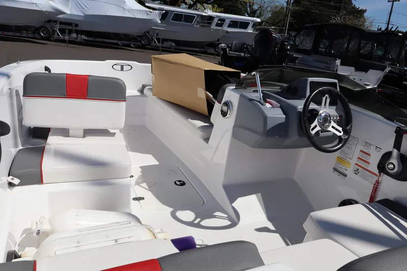 Slide: The Image of 2023 White River Tahoe boat interior with steering wheel and seating, parked outdoors. - 9