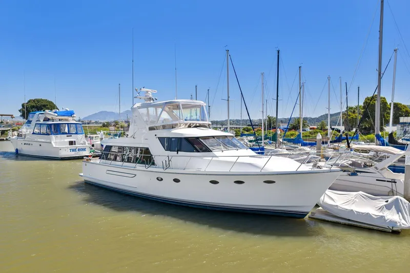 Slide: The Image of 1991 Ocean Alexander 520 Pilothouse yacht docked in a marina under clear blue skies. - 2