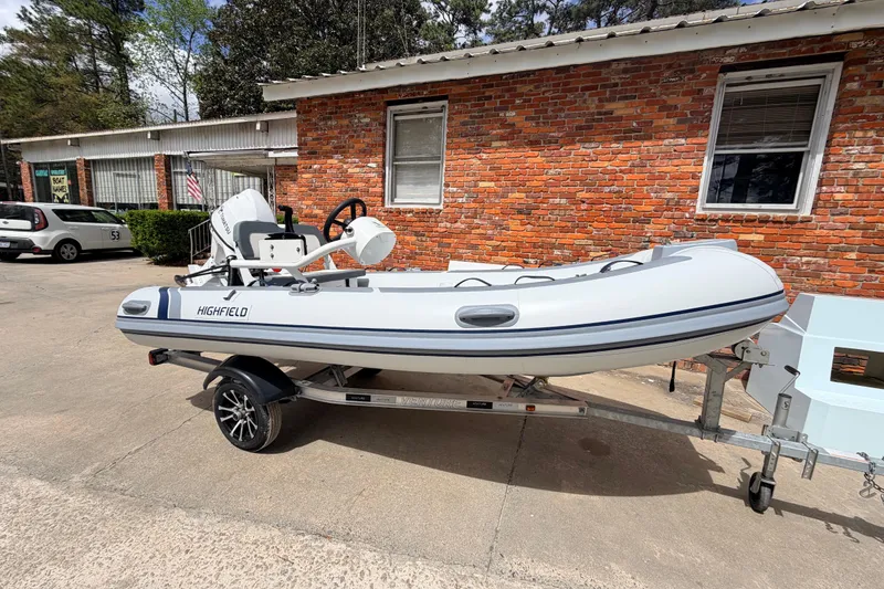 The Image of 2023 Highfield Classic 380 FCT inflatable boat on trailer, parked by brick building. - 0