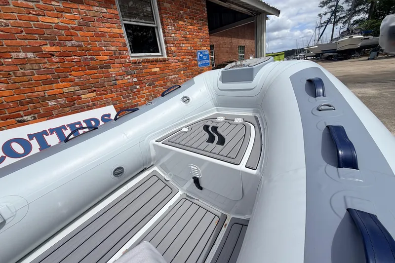 Slide: The Image of 2023 Highfield Classic 380 FCT inflatable boat with gray deck, docked near brick wall. - 3