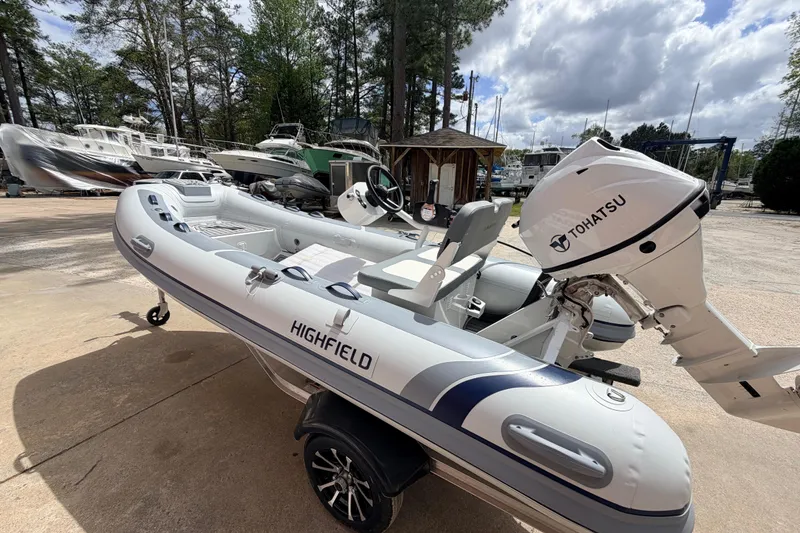 Slide: The Image of 2023 Highfield Classic 380 FCT inflatable boat with Tohatsu outboard motor in a marina setting. - 4