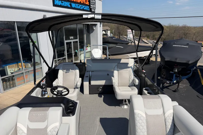 Slide: The Image of 2026 Crest Conquest 250 SLSC pontoon boat with luxurious seating and canopy at dealership. - 13